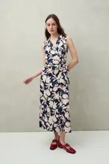 Vestido midi sin mangas, con estampado floral en tonos beige y azul marino. Diseño cruzado tipo wrap con lazo en la cintura y cuello sastrero.