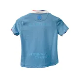 Camiseta de fútbol Umbro del Club Nacional de Football, modelo Away 3 2024 para niños. Diseño celeste con cuello tipo polo con detalles en blanco y rojo. Incluye logo de Umbro, escudo del club y sponsor Antel en el frente.
