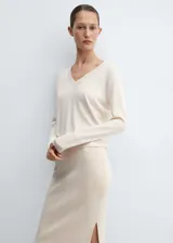 Sweater de punto fino color crudo, con escote en V y mangas largas.