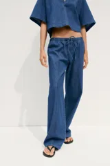 Pantalón de jean azul con cintura elástica ajustable con cordones, tiro medio y bolsillos de parche en la parte trasera.