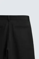 Pantalón negro de corte ancho, con pinzas en la cintura, bolsillos laterales y traseros de ojal.