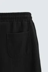 Bermuda negra de corte relaxed fit, con cintura elástica ajustable con cordón, bolsillos frontales y bolsillo trasero de parche.