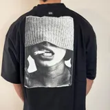 Remera negra de corte oversize y mangas cortas, con estampa en la espalda de una fotografía en blanco y negro de una persona fumando.