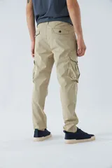 Pantalón cargo color marrón, corte slim, con cierre y botón en la cintura, pasacintos y bolsillos cargo con botones.