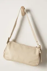 Bolso bandolera color crema, de cuero, con correa ancha ajustable con hebilla dorada.