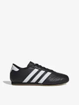 Zapatillas Adidas de cuero negro con las tres rayas blancas y suela color caramelo.