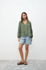 Camisa verde militar de crepe con escote en V, mangas largas abullonadas y detalle de cordón con borlas en el escote.