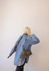 Bandolera de cuero color rojo con detalles en negro, con correa regulable y cierre superior con cremallera.