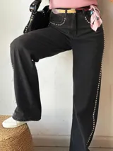 Pantalón de jean negro de corte recto con detalles de tachas plateadas en los bolsillos delanteros y a lo largo de la costura lateral.