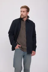 Camisa negra de manga larga con cuello clásico y cierre frontal con botones. Tiene un bolsillo de parche en el pecho izquierdo.