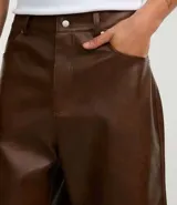 Bermuda masculina de cuero sintético color marrón, corte holgado, con cintura con trabillas, cierre tradicional, bolsillos delanteros y traseros, y efecto desteñido.