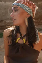 Top marrón con espalda descubierta y tiras para atar al cuello. Presenta una arandela amarilla en el centro del busto.