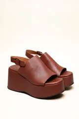 Sandalias con plataforma color marrón, con capellada envolvente, pulsera trasera ajustable y hebilla metálica.