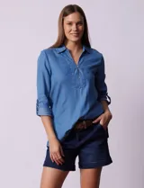 Blusa celeste de lyocell con cuello a la base con solapa, escote en V y abertura central con botones. Manga 3/4 regulable con presilla y botón.