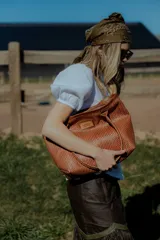 Bolso tipo tote de cuero color marrón con diseño tejido. Tiene bolsillo interno, porta llaves y cierre.
