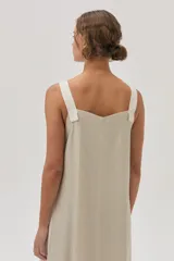 Vestido largo color beige de lino metalizado, con tirantes anchos a contratono y corte recto con abertura lateral.