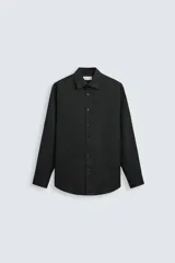 Camisa negra de manga larga con cuello italiano y cierre frontal de botonadura. Presenta un tejido con estructura de fácil cuidado.