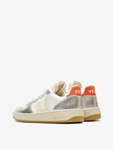 Zapatillas Veja V-10 blancas con detalles en plateado y naranja. Fabricadas con cuero orgánico y suela de caucho amazónico.