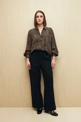 Camisa marrón con estampado animal print negro, de calce relajado, cuello clásico, abotonadura frontal y mangas largas con puños camiseros.