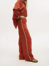 Pantalón de lino color marrón claro, de pierna ancha y tiro alto. Presenta un pequeño elástico en la parte trasera de la pretina y detalle al costado tipo naval.