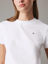 Remera blanca de algodón con cuello redondo, mangas cortas y corte relaxed. Presenta un pequeño logo de la marca bordado en el pecho y un estampado con el logo de Calvin Klein en la espalda.