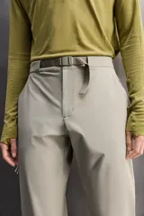 Pantalón de hombre color beige/caqui, de corte regular fit, confeccionado en tejido técnico compacto con elasticidad. Presenta cintura ajustable con cinturón a contraste, bolsillos frontales, bolsillo trasero con cierre de cremallera oculta y bolsillo cargo con cierre de cremallera oculta en la pernera.