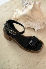 Sandalias de cuero color crudo, con tira ancha sobre los dedos, pulsera con hebilla al tobillo y taco cuadrado de madera.