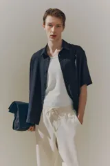 Camisa negra de manga corta en mezcla de lino y viscosa, con cuello inglés, tapeta lisa, canesú en la espalda y bajo recto. Corte holgado.