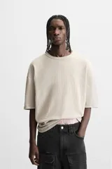 Camiseta color gris verdoso de punto tejido en hilatura de algodón, con cuello redondo, manga corta, efecto lavado y acabados irregulares.
