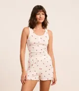 Conjunto de pijama short doll blanco con estampado de cerezas rojas, confeccionado en tejido rib. Incluye musculosa con puño y short con cintura elástica y bajo frufru.