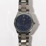 Reloj de pulsera plateado con esfera azul texturizada y agujas plateadas.