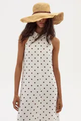 Vestido midi blanco con lunares marrones, escote halter y corte en línea A. Confeccionado en lino 100% natural con terminación metalizada.