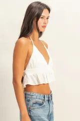 Top blanco con textura y peplum, escote halter y tirantes finos.