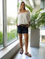 Short de jean azul oscuro con pretina con pasadores, botón y cierre. Delantera con bolsillos. Botón en bolsillos traseros. Incluye cinturón trenzado marrón con hebilla redonda dorada.