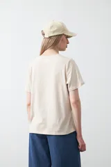 Remera blanca de algodón de manga corta, con cuello redondo y bordado frontal en hilo color beige claro con la palabra "J'adore" en tipografía cursiva.