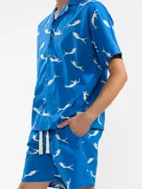 Camisa celeste con estampado de sirenas blancas, de corte recto con cuello camisero y mangas cortas.