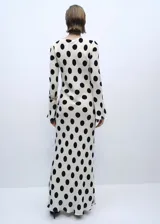 Vestido midi blanco con lunares negros, de mangas largas acampanadas y cuello redondo.