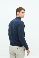 Buzo de punto color gris claro con medio cierre, cuello alto y logo bordado.