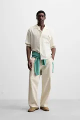 Camisa negra de corte relaxed fit, confeccionada en tejido con mezcla de modal. Tiene cuello bowling, manga corta, bolsillo de parche en el pecho y cierre frontal con botones.