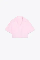Camisa corta rosa de popelín, con cuello solapa, escote pico, manga corta, bolsillos delanteros de plastrón y cierre frontal con botones.