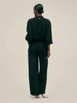 Pantalón palazzo negro de crepe con cintura elastizada, bolsillos laterales y terminaciones con logo en cobre.
