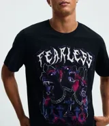 Remera negra de algodón con estampado frontal de tres perros tipo doberman con cadenas y cruces, y la palabra "FEARLESS" en la parte superior.