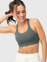 Top deportivo gris con breteles anchos cruzados en la espalda y costuras decorativas en el frente.