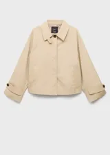 Chaqueta corta de algodón y poliéster color beige, con cuello camisero, cierre frontal de botones y diseño oversize. Posee mangas largas con trabillas ajustables y dos bolsillos laterales.
