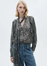 Blusa de manga larga con estampado animal print en tonos grises y blancos. Tiene cuello redondo con lazo para atar.