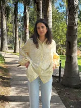 Camisa amarilla clara con bordado de flores blancas, de corte recto y mangas largas abullonadas.