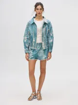 Short biker ajustado de lycra con estampado abstracto y difuminado en tonos verdes, naranjas, azules y rosados. Presenta costuras visibles en contraste y un pequeño logo bordado en la pierna derecha.