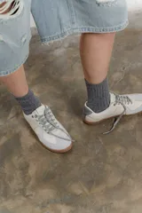 Zapatillas urbanas de cuero color crema con puntera y talón en gamuza gris, suela de goma marrón y cordones grises.