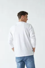 Remera blanca de manga larga con cuello redondo y estampado de un edificio antiguo.