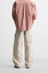 Pantalón color marrón con efecto lavado, corte relaxed fit, cinco bolsillos, aplicación de tira y bolsillo multifunción en perneras, cierre frontal con cremallera y botón.